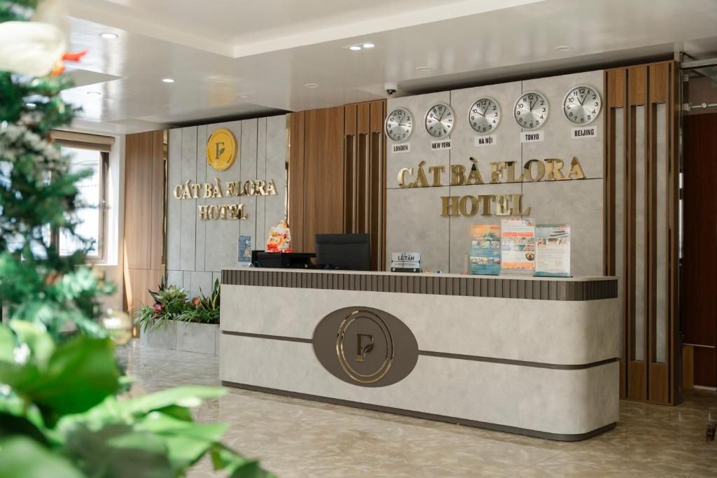 Un comptoir d’accueil d’hôtel au design moderne, agrémenté d’un logo, d’horloges indiquant l’heure de différentes villes et d’un comptoir de réception.