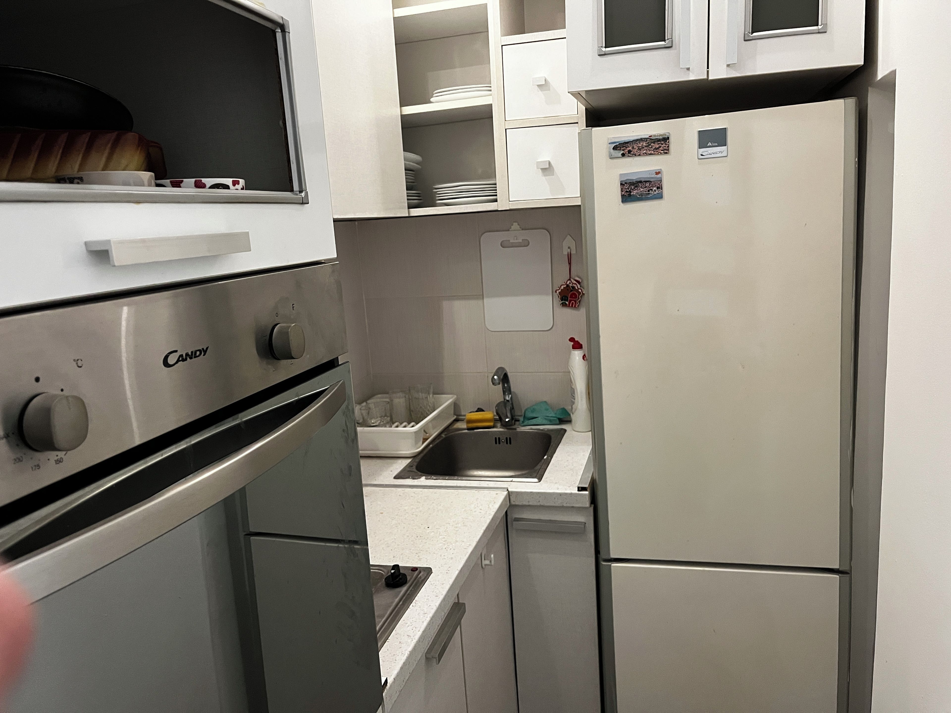 A compact kitchen with a built-in oven, a sink, and a refrigerator.