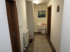 Un corridoio stretto con un termosifone, un cestino e un lavandino piccolo con un asciugamano.