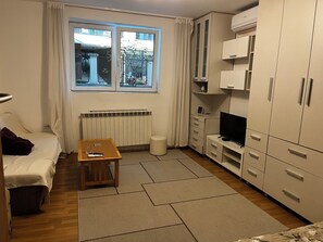 A compact room with a bed, a small table, a television, and a wardrobe. - Perfect 1-bedroom apartment with AC in fabulous Beograd (Beograd)