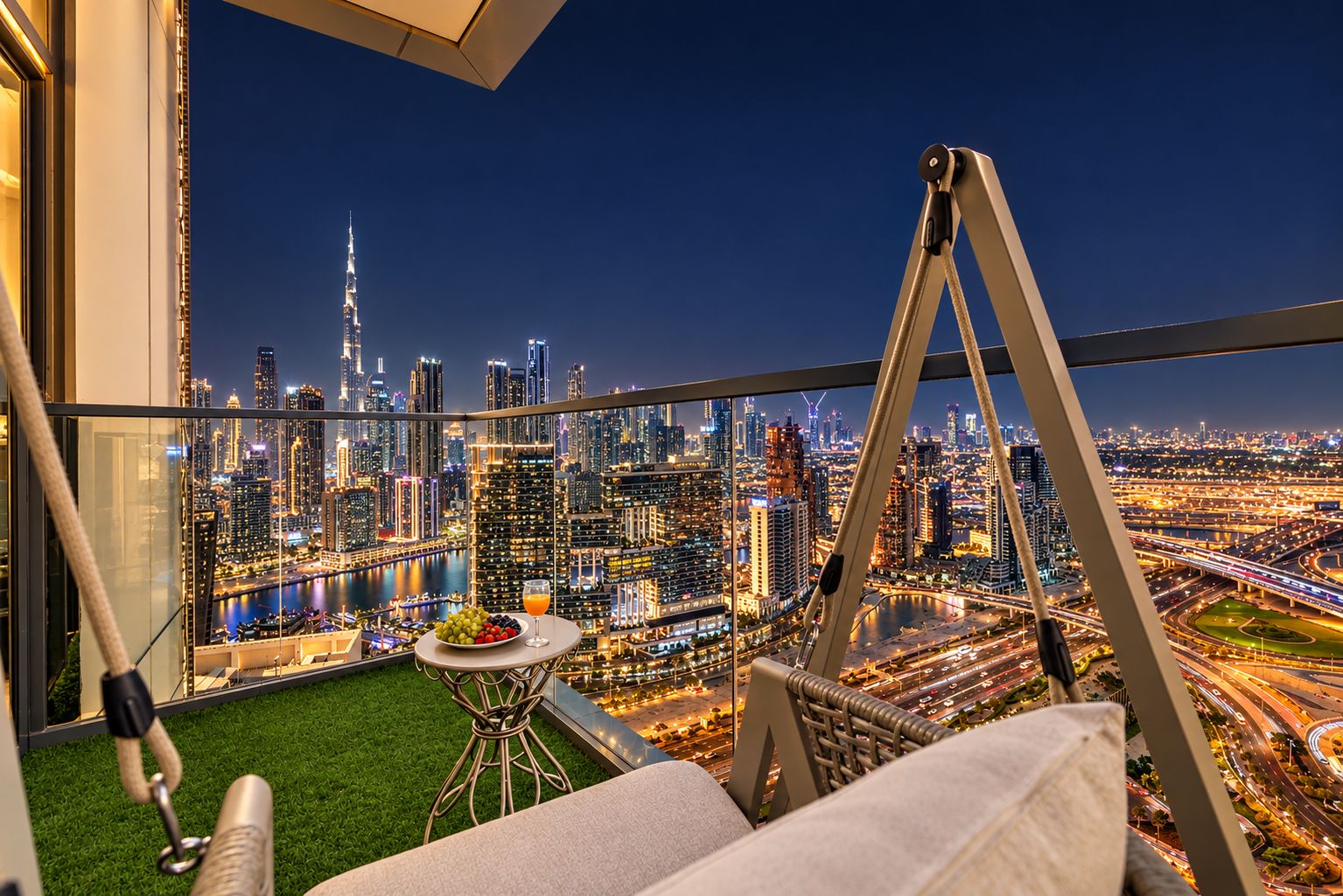 Ein Balkon mit Blick auf die Stadt, ein Tisch mit Obst und Getränken sowie ein Schaukelstuhl.