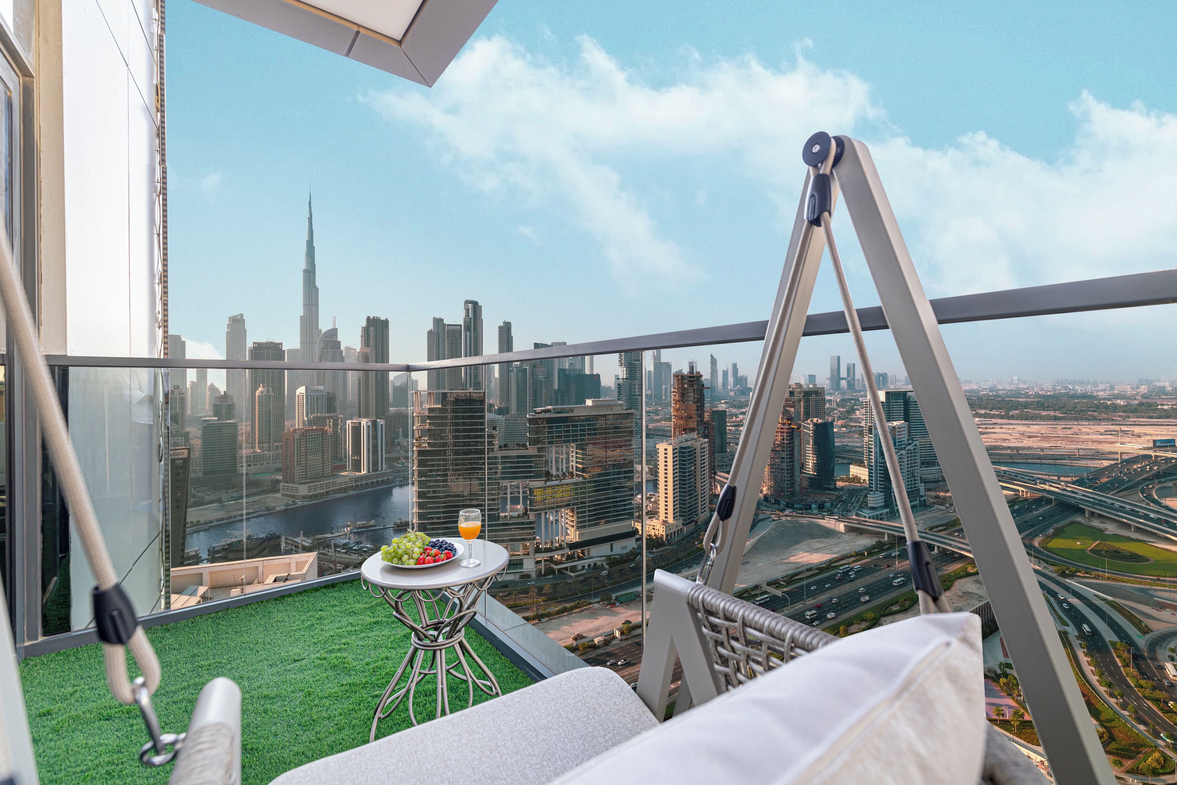 A balcony with a table, a chair, and a view of a city skyline.