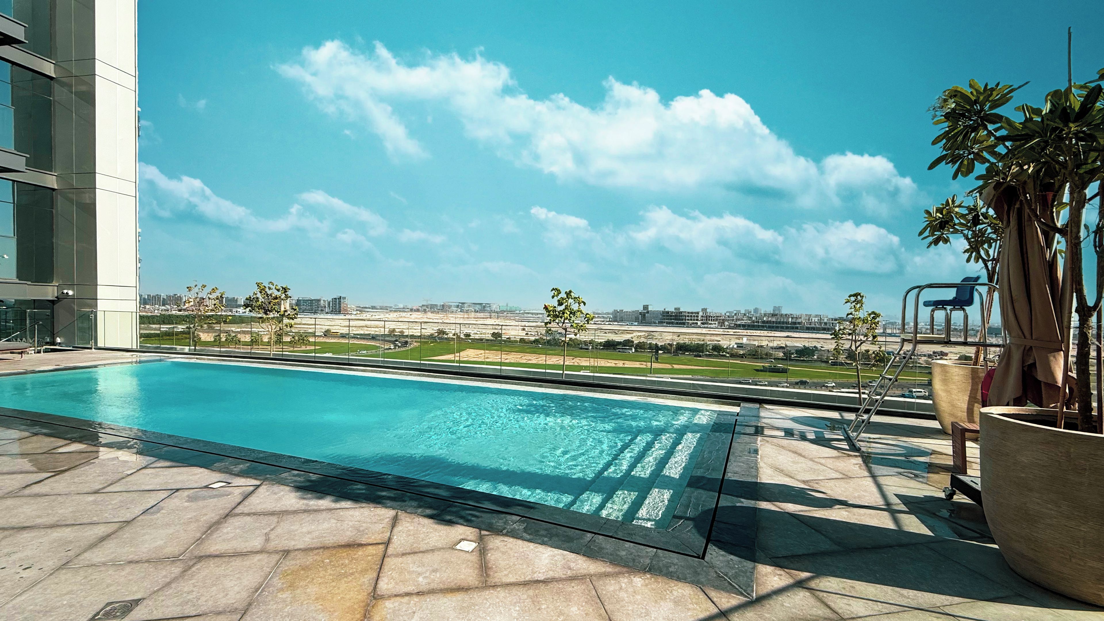 A rooftop pool with a clear view of the city skyline and distant airport.