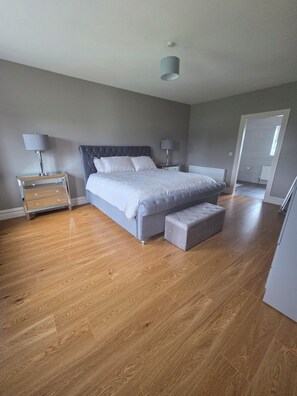 Quarto com cama, mesas de cabeceira e espelho.