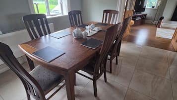 A dining area with a wooden table, chairs, and a view of the outdoors through a window.