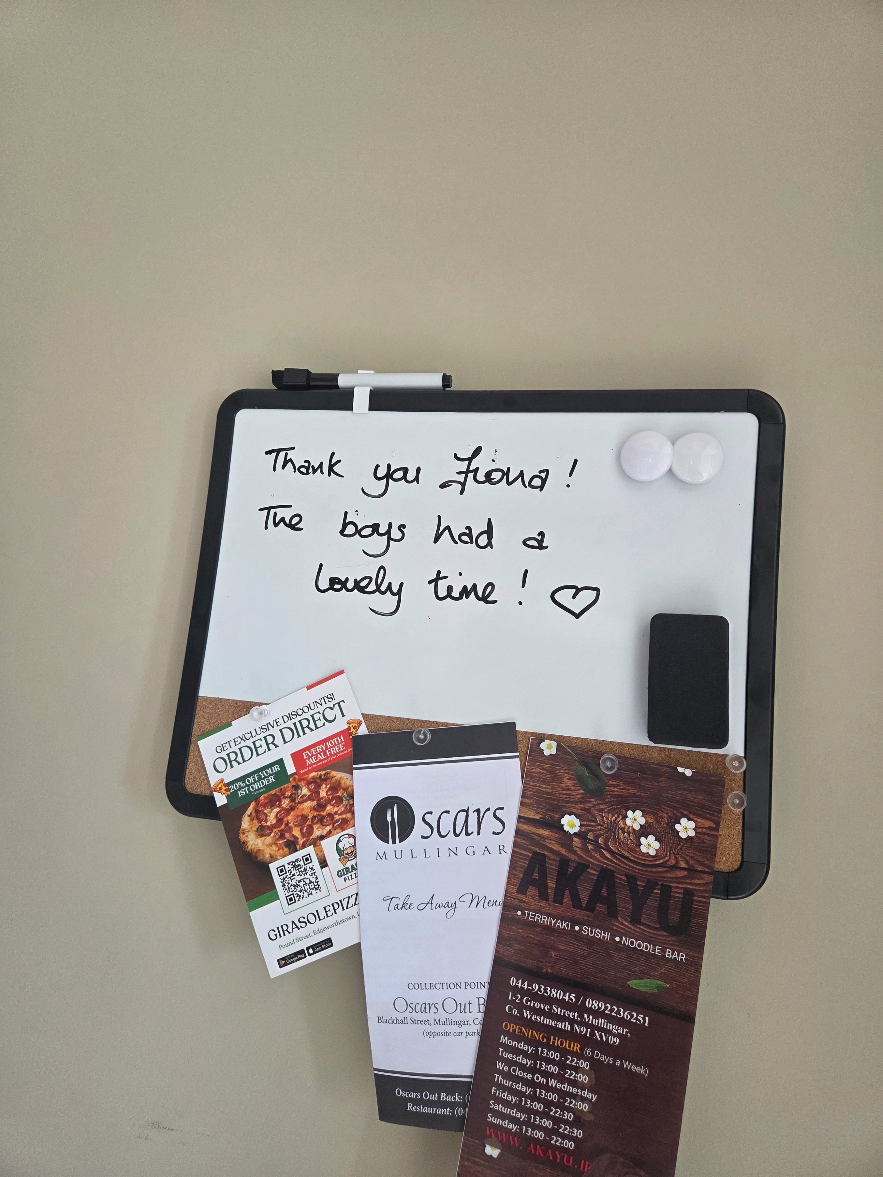 A whiteboard with a handwritten note, a pizza coupon, a take-away menu, and a receipt.