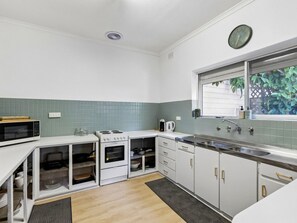A compact kitchen with white cabinets, a microwave, an oven, and a sink.