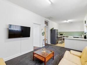 Ein modernes Wohnzimmer mit Flachbildfernseher, Glastisch und Sofa.