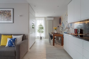 A modern kitchen with white cabinets, a dining table, and a coffee machine. - Cracow | Poznańska 10 | Comfortable Apartment | Air conditioning (Kraków)