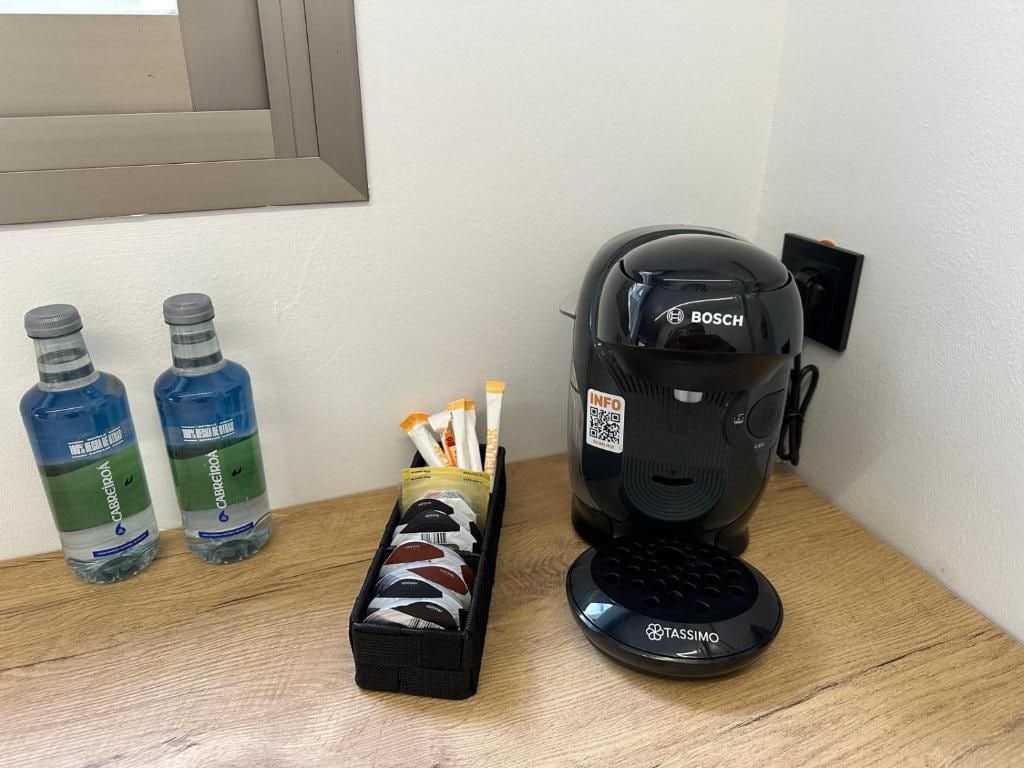 Una cafetera, dos botellas de agua y una caja de pañuelos sobre una superficie de madera.