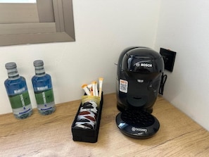 A coffee machine, two water bottles, and a box of tissues on a wooden surface.