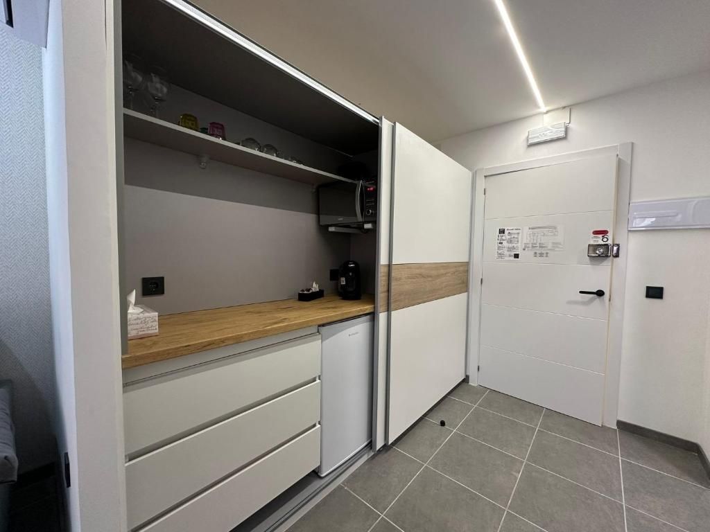 Cocina compacta con microondas, cafetera y una repisa con vasos.