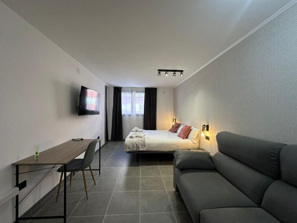 Una habitación de hotel moderna con cama, sofá, escritorio y televisión.