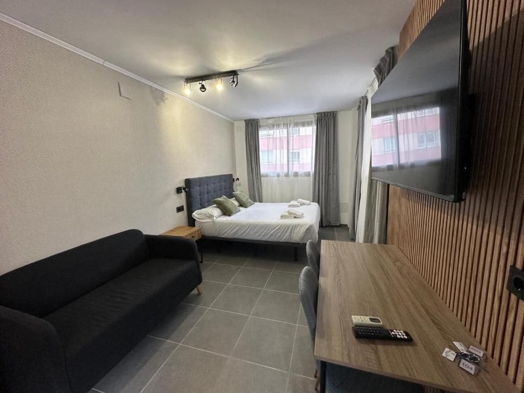 A hotel room with a bed, a sofa, a desk, and a TV.