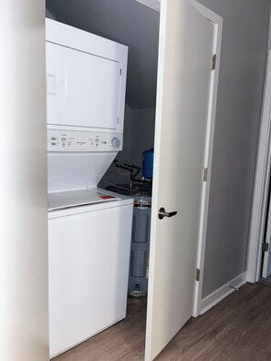 A laundry room with a white washing machine, a blue water heater, and a door leading to another room. - The Chosen Charm Cozy Intimate 1-BR just minutes from downtown Nashville, TN. (Nashville)