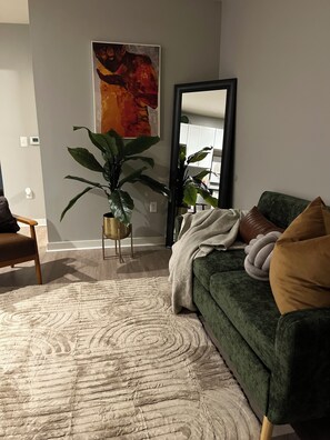 A living room with a green sofa, a large mirror, and a potted plant. - The Chosen Charm Cozy Intimate 1-BR just minutes from downtown Nashville, TN. (Nashville)