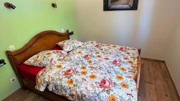 A room with a bed, a wooden floor, a green wall, and a painting.