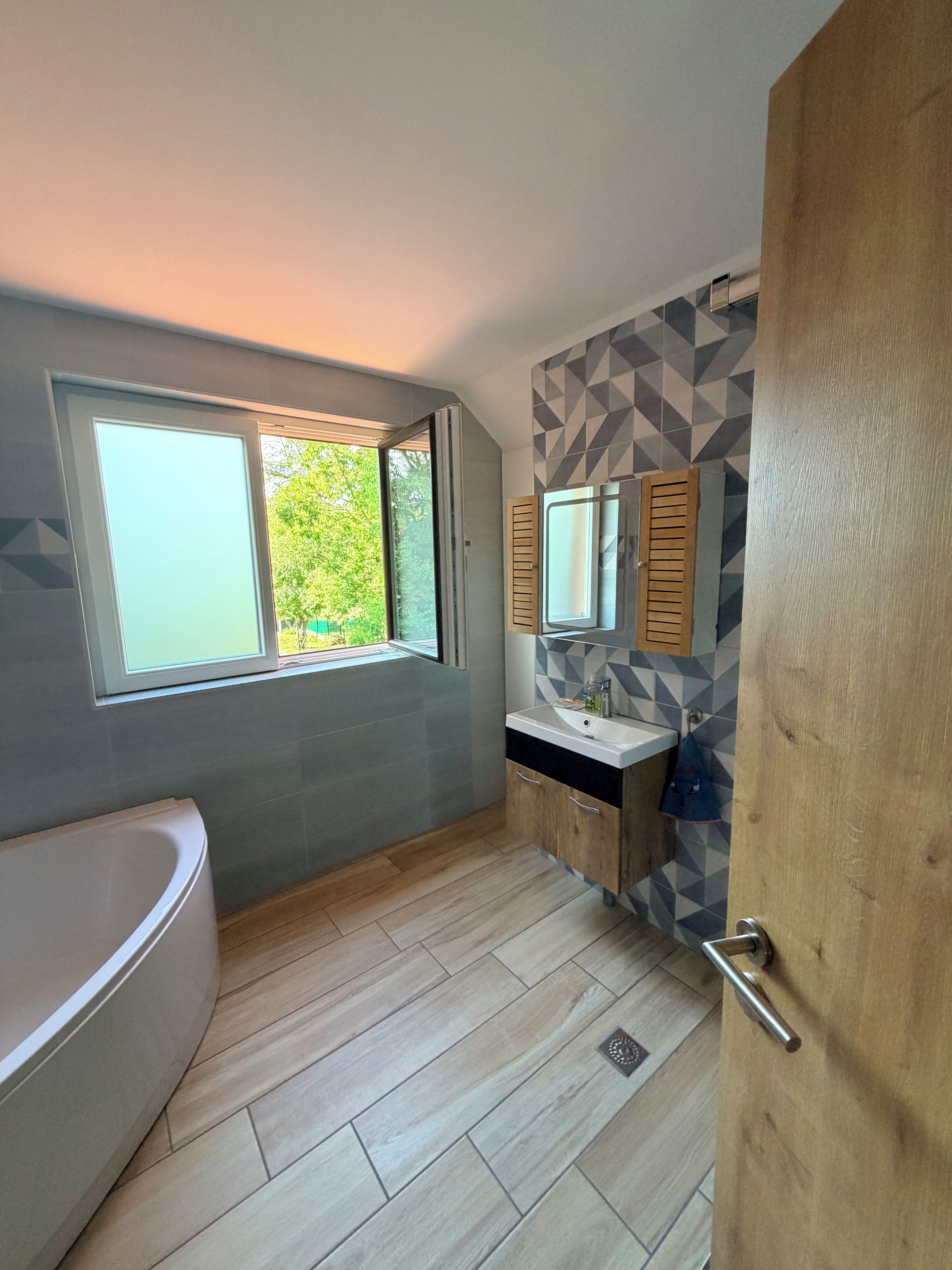 Un baño moderno con bañera, lavamanos y ventana.