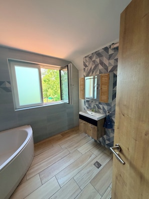 A modern bathroom with a bathtub, a sink, and a window. - Gieder (Uffheim)