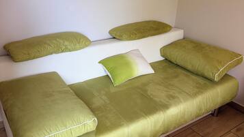 Una cama con cojines verdes y un cabecero blanco en una habitación con suelo de madera.