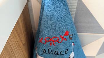 A blue towel with embroidered birds and text, hanging on a wooden surface.