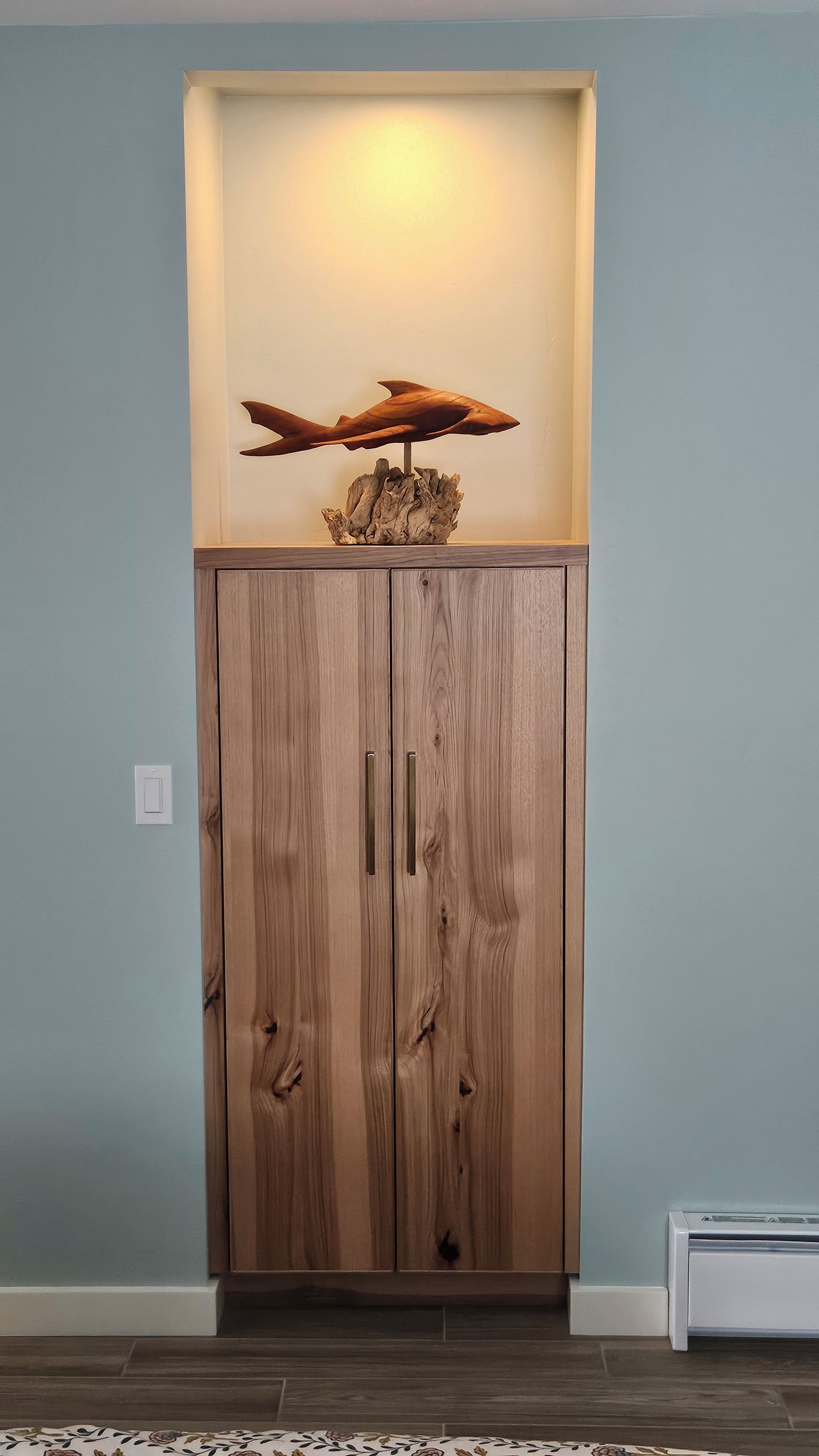 Un meuble en bois doté de deux portes et orné d’un élément décoratif sur le dessus.