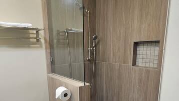 A modern bathroom with a glass-enclosed shower, a toilet, and a towel rack.