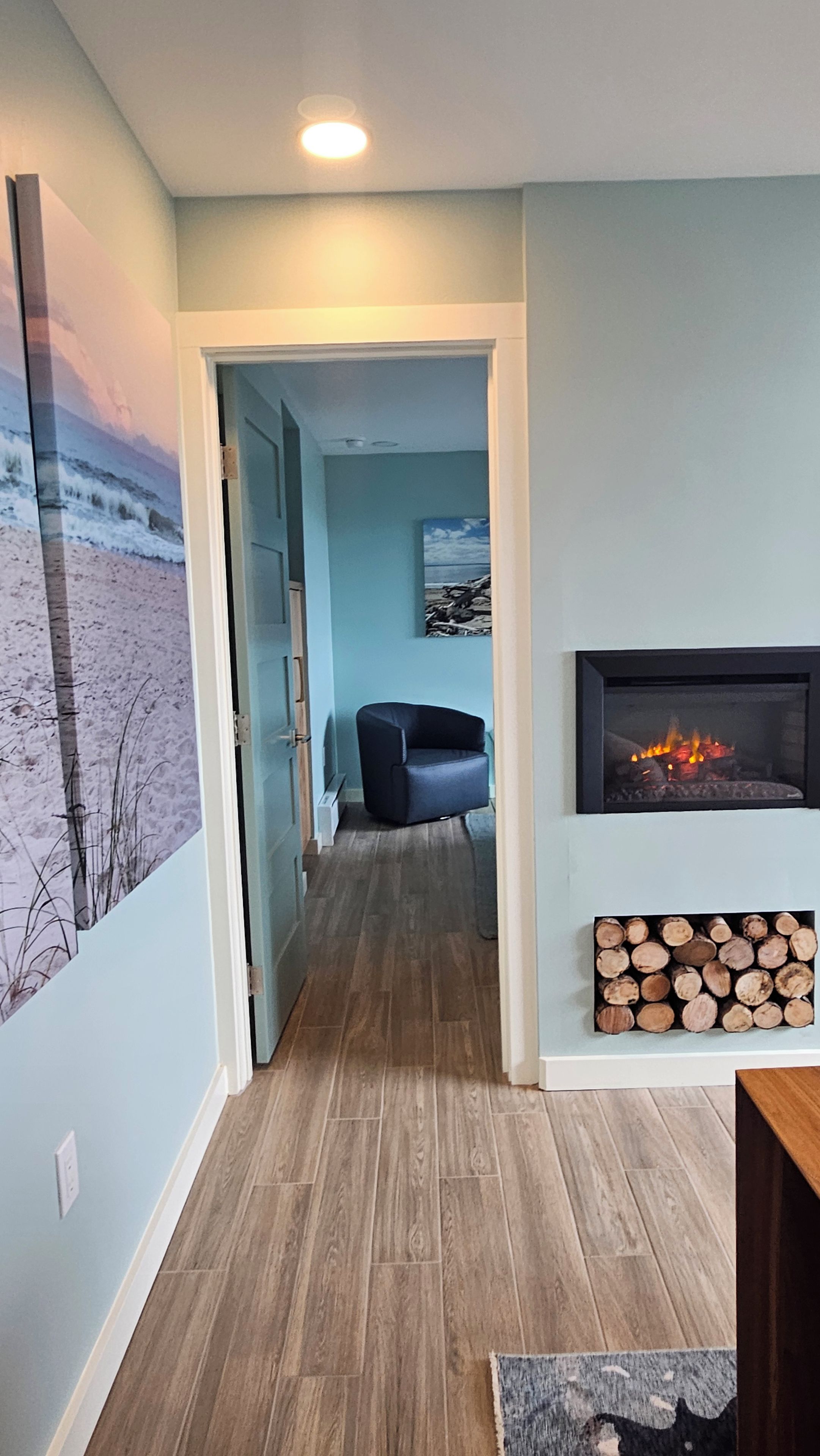 Un couloir avec un plancher en bois, un mur bleu, une cheminée et une chaise.