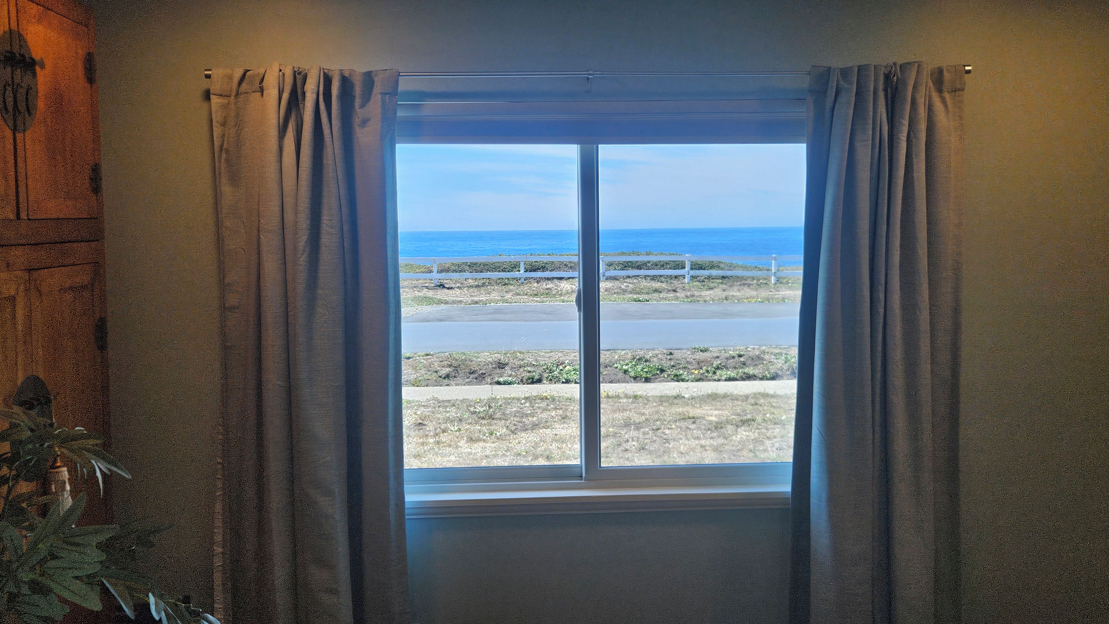 A window with a view of the ocean and a road.