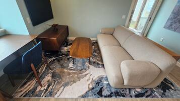 Un salon avec un canapé, une table basse et un téléviseur posé sur un meuble.