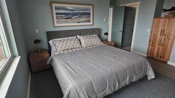 Une chambre à coucher avec un lit, des tables de chevet, un tableau, une armoire et une porte.
