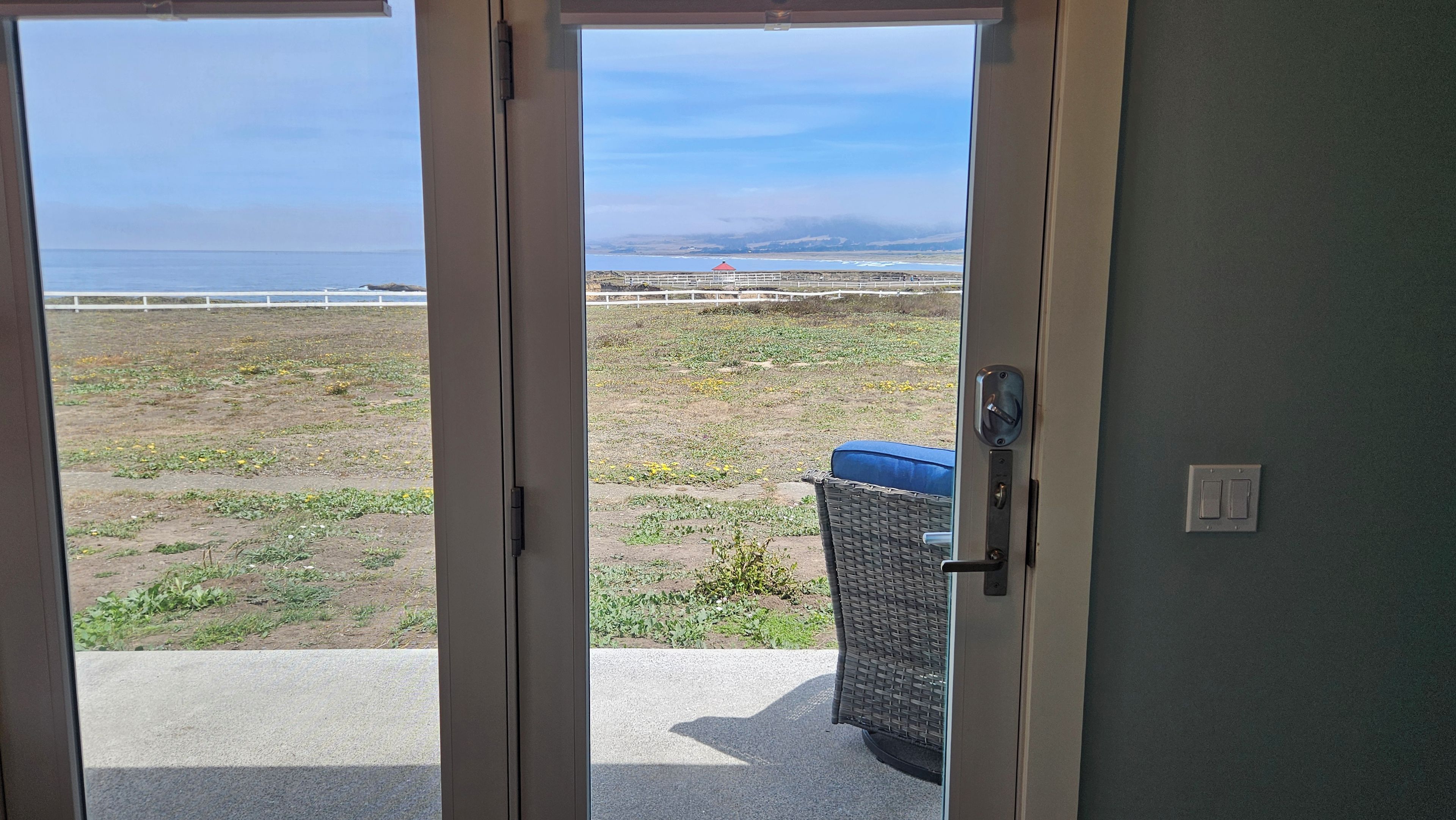 A view through a door to a balcony with a view of the beach and ocean.