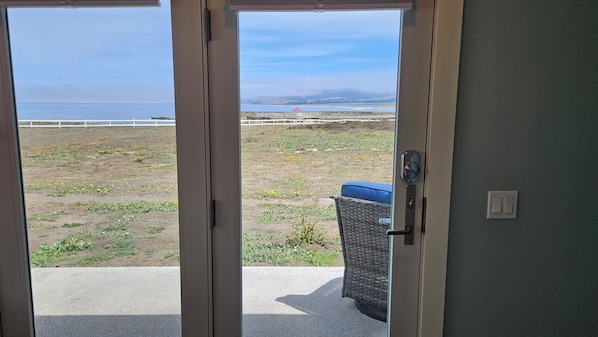 A view through a door to a balcony with a view of the beach and ocean.