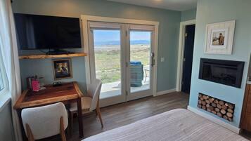 A room with a wooden desk, a chair, a television mounted above the desk, a fireplace, and a large sliding glass door leading to an outdoor area.