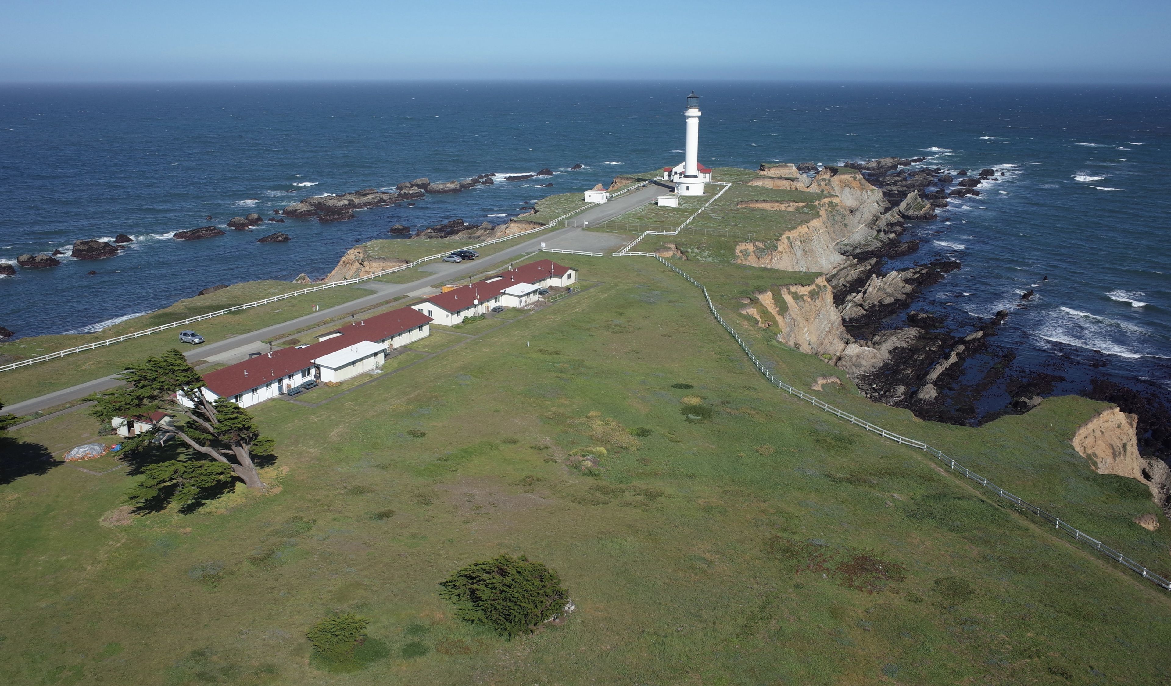 A coastal area with a lighthouse, grassy terrain, and rocky cliffs.