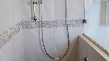 Eine Dusche mit Handbrause und fest installierter Duscharmatur.