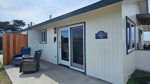 A building with a sliding glass door, two wicker chairs with blue cushions, and a sign reading 'Raven Studio.' - Point Arena Lighthouse - Raven Studio (Point Arena)
