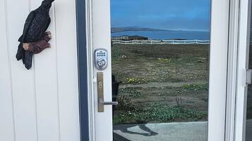 A door with a keypad lock, a bird sculpture, and a view of the ocean.