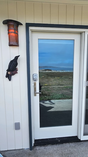 A door with a keypad lock, a bird sculpture, and a view of the ocean. - Point Arena Lighthouse - Raven Studio (Point Arena)