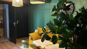 Une pièce chaleureuse avec un canapé, une table basse en bois, une grande plante et une horloge murale.