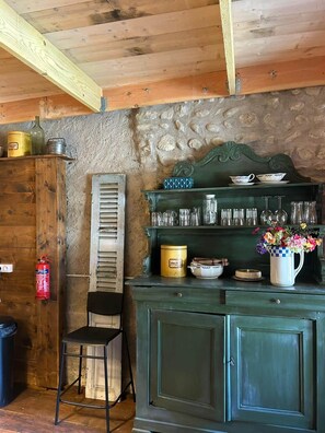 Een landelijke keuken met houten kastjes, een stenen muur en een metalen brandblusser.