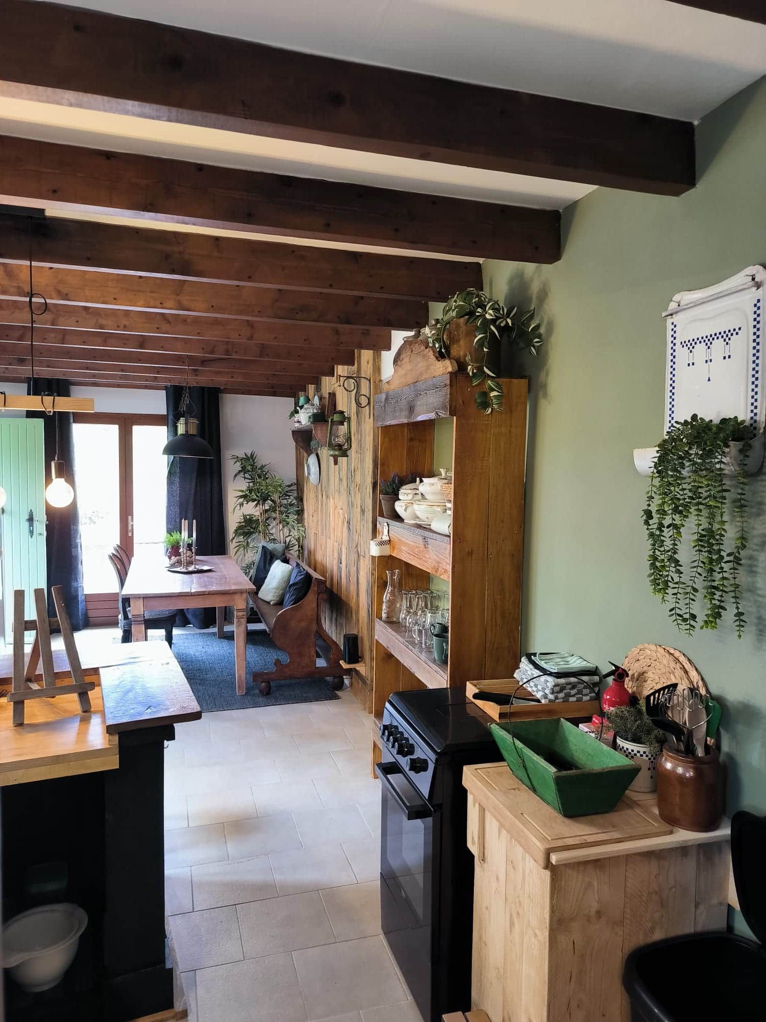 Une cuisine rustique avec des poutres en bois, un coin repas avec une table et des chaises, ainsi que divers ustensiles de cuisine et plantes.