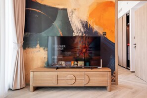 A flat-screen TV mounted on a wooden cabinet with a modern abstract wall art in the background. - Urban Escape in Business Bay (Dubai)