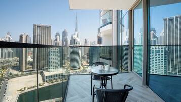 Un balcone con ringhiera in vetro che si affaccia su un panorama urbano con edifici moderni e un fiume.