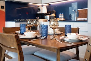 A dining table set with plates, bowls, glasses, and cutlery, with a blue patterned vase and a corked container. - Urban Escape in Business Bay (Dubai)