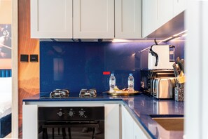A modern kitchen with a dark backsplash, stainless steel appliances, and a breakfast bar. - Urban Escape in Business Bay (Dubai)