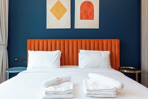A hotel room with a large bed, two pillows, a nightstand, a round table, and artwork on the wall. - Urban Escape in Business Bay (Dubai)