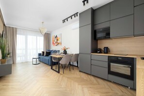 A modern kitchen with grey cabinets, a wooden countertop, and a built-in oven. - Katowice | Zabrska 15 | Modern Apartment | Air conditioning (Katowice)