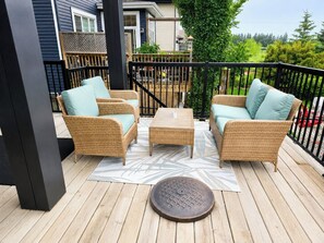 A covered outdoor seating area with wicker furniture and a central table. - Elegant and Spacious Getaway in St. Albert. 4 BR's, AC and Premium Amenities. (St. Albert)