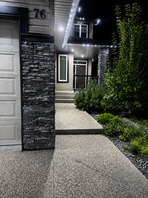 A modern house with a stone facade, a garage, and a well-lit entrance. - Elegant and Spacious Getaway in St. Albert. 4 BR's, AC and Premium Amenities. (St. Albert)